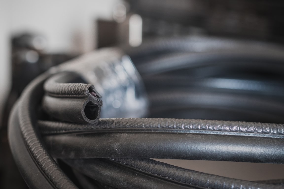 Rubber edge trim, cut at one end showing the unique profile, coiled and resting on the floor