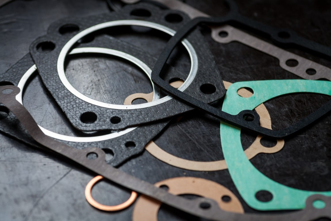 Various rubber gaskets, black, green, and tan-coloured lie on a black cutting mat