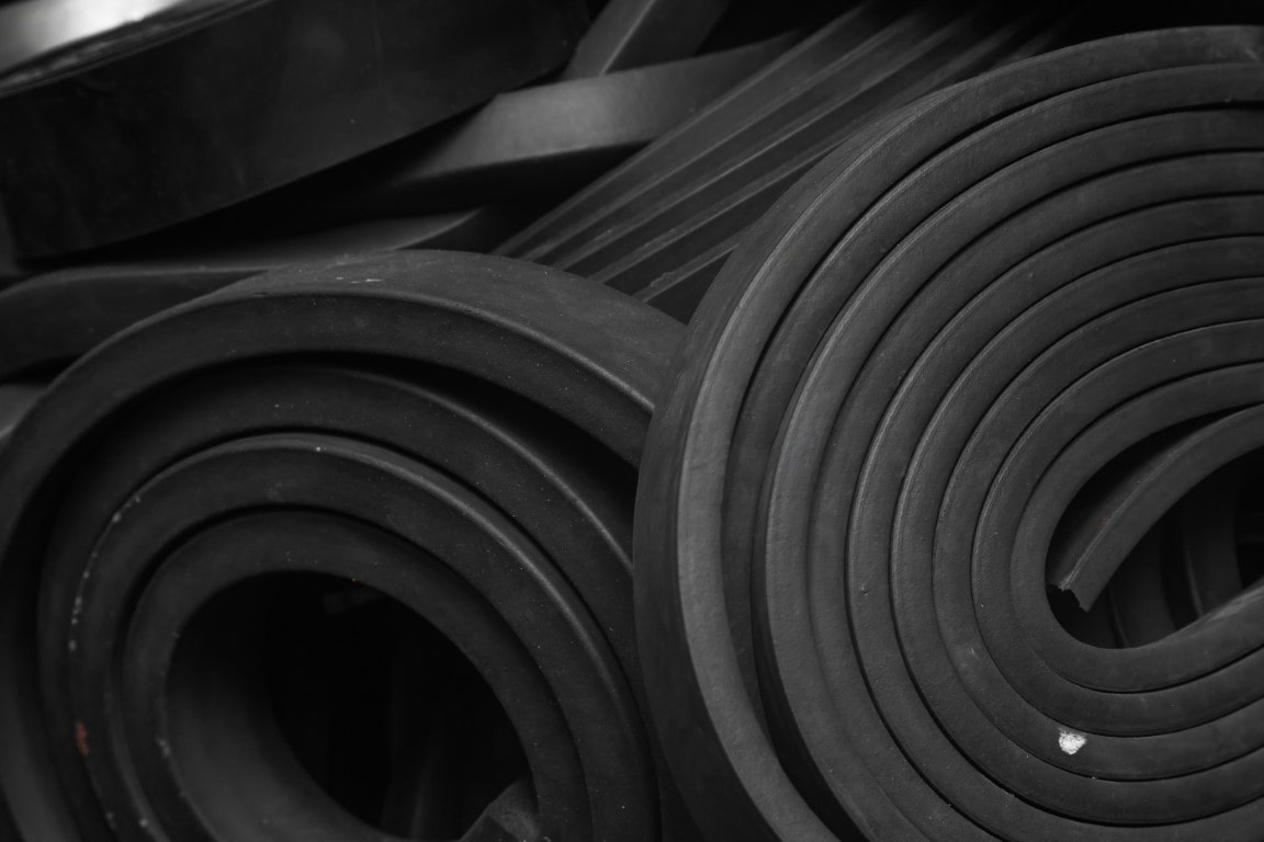 Black rubber strip coiled and stacked haphazardly on top of one another